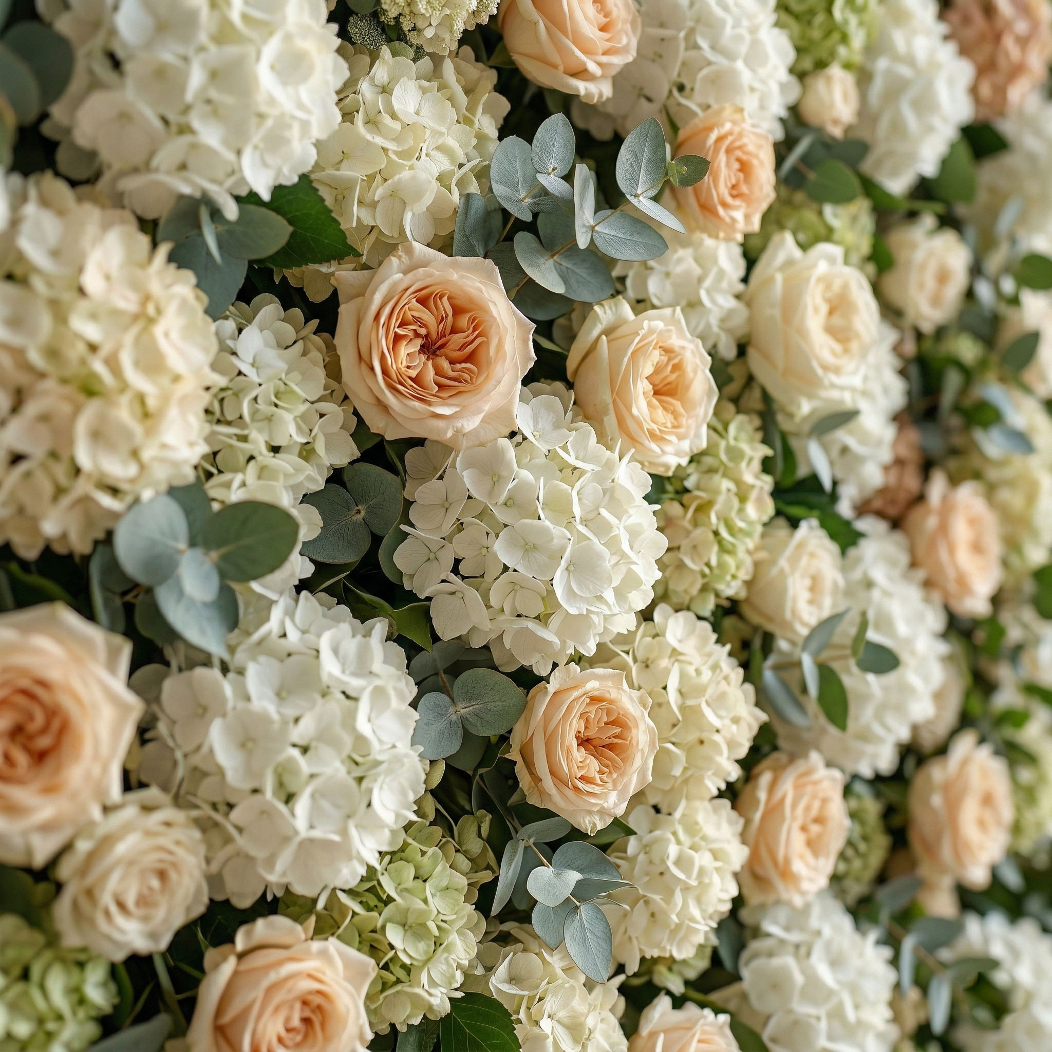 Close-up of green and white flower wall with eucalyptus and peach Real Touch roses